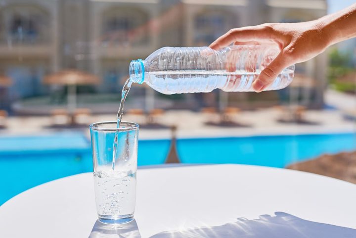 woman-hand-pouring-water-in-a-glass-from-bottle